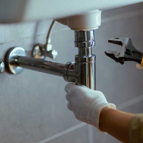 Un plombier muni d'une pince répare un évier dans l'Outaouais Un plombier muni d'une pince répare un évier dans l'Outaouais